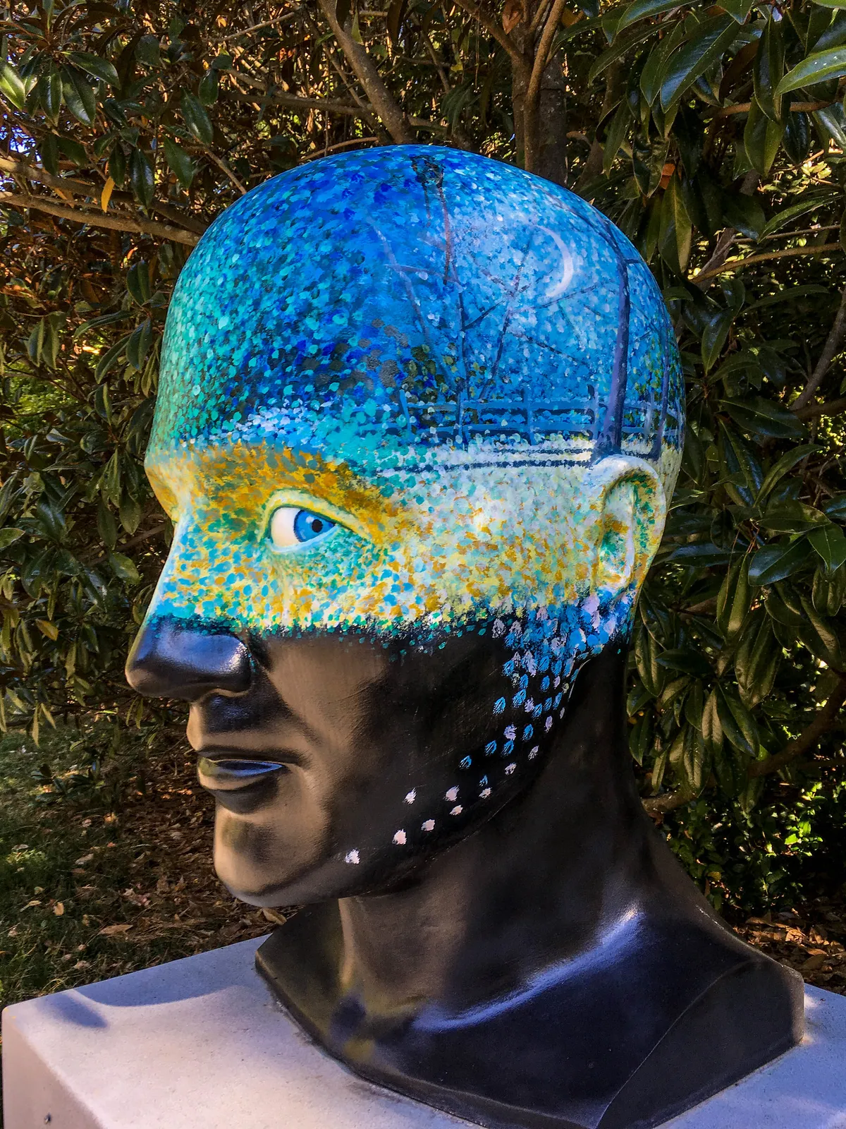 A painted head sculpture among the plantings at Aldridge Gardens in Hoover.