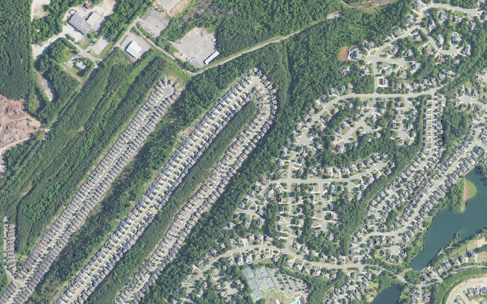 Aerial view of Lake Cyrus in west Hoover, with rows of townhomes, a pond and tennis courts among the houses.